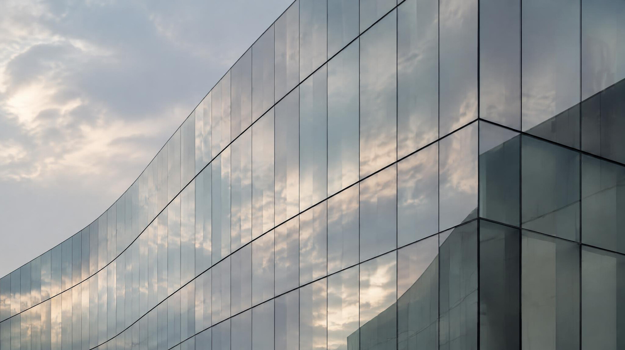 Modern glass building facade reflecting the sky